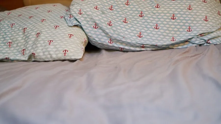 Couple resting peacefully together on bed with multiple comfortable pillows in cozy bedroom setting