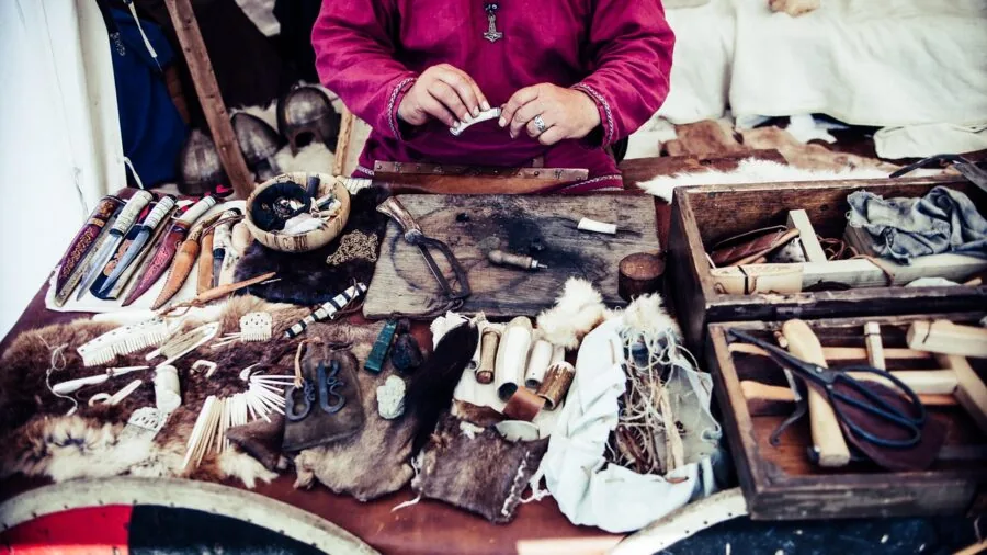 Crafter working with diverse materials including paper, leather, and foam on wooden workspace