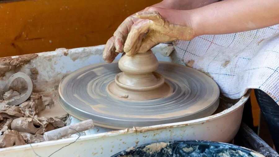 Creative artist working with clay at wooden studio table with natural light