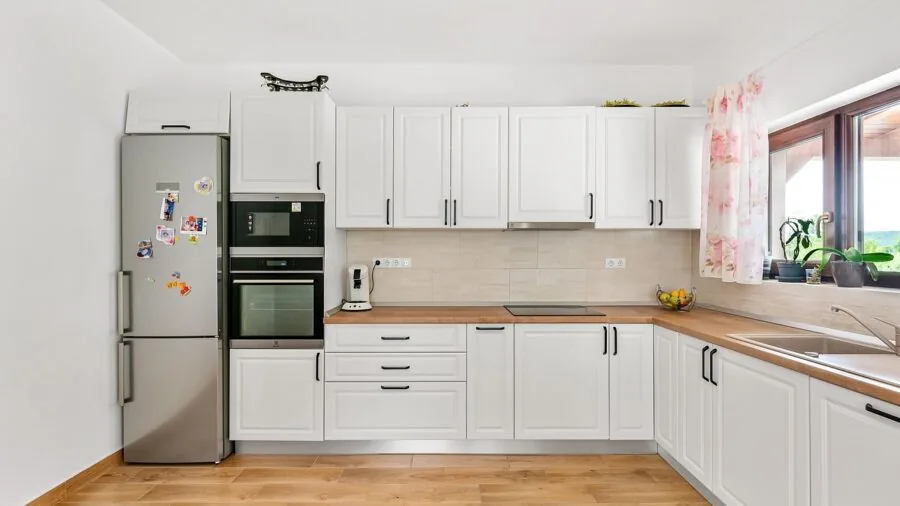 Curious toddler reaching toward lower kitchen cabinet while parent supervises in home setting