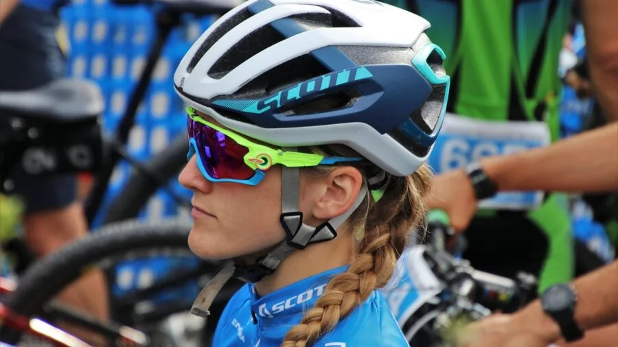 Cyclist cleaning and maintaining eyewear after outdoor ride, focus on gear care and maintenance