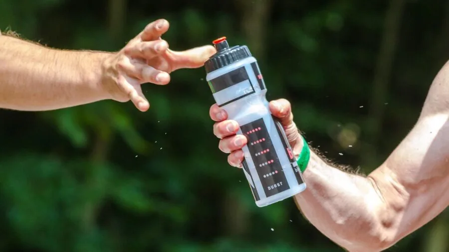 Cyclist comparing different water bottle choices during outdoor biking adventure on sunny day