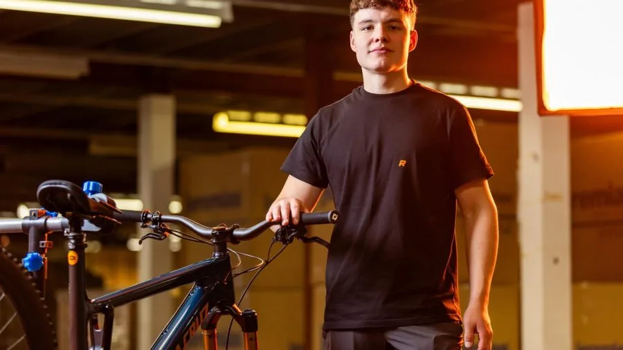 Cyclist fine-tuning saddle position on mountain bike in natural setting