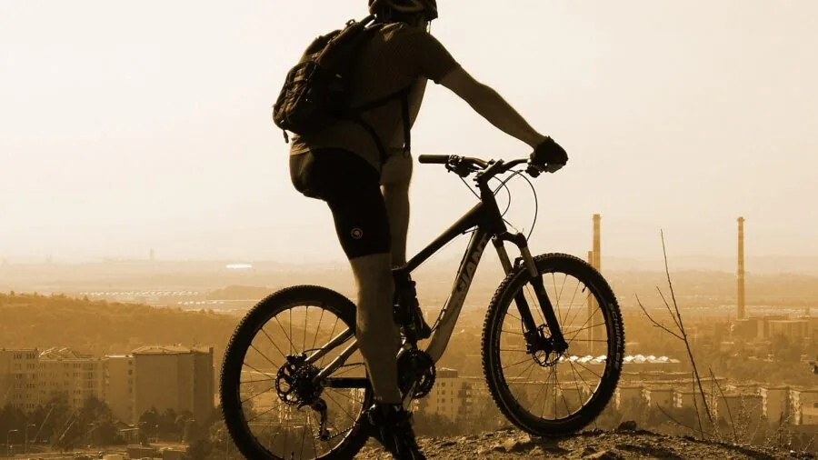 Cyclist inspecting frame-mounted pump on bicycle down tube during outdoor ride