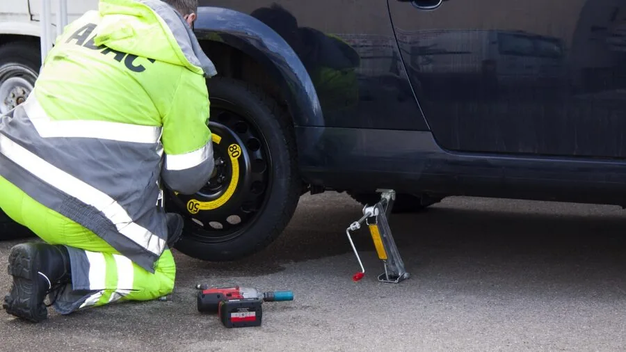 Cyclist inspecting punctured bike tire on trail, examining damage