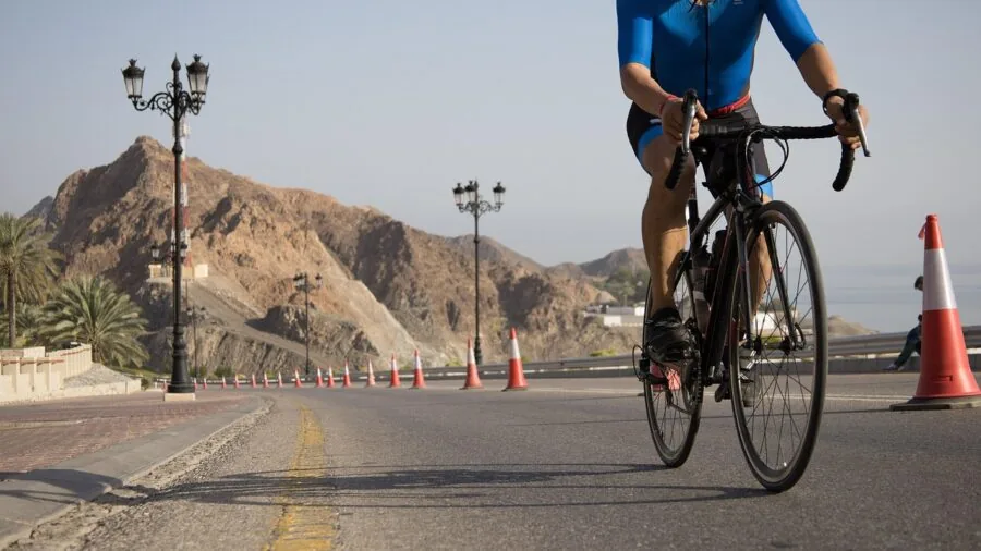 Cyclist riding a road bike on a scenic mountain road during golden hour with natural landscape in background