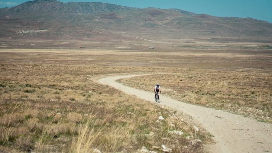 Cyclist riding mountain bike on rough gravel terrain with water bottle secured in cage