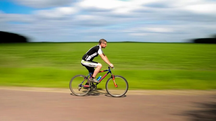 Cyclist riding on dark road at night with bike lights illuminating the path ahead
