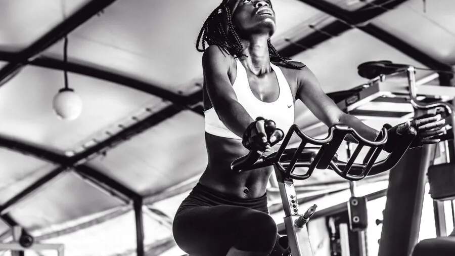 Dedicated cyclist training indoors on stationary bike with focused intensity during structured workout session