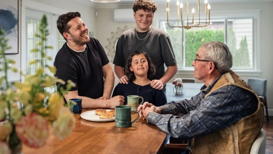 Diverse family members of different ages gathered around a table playing a game together indoors