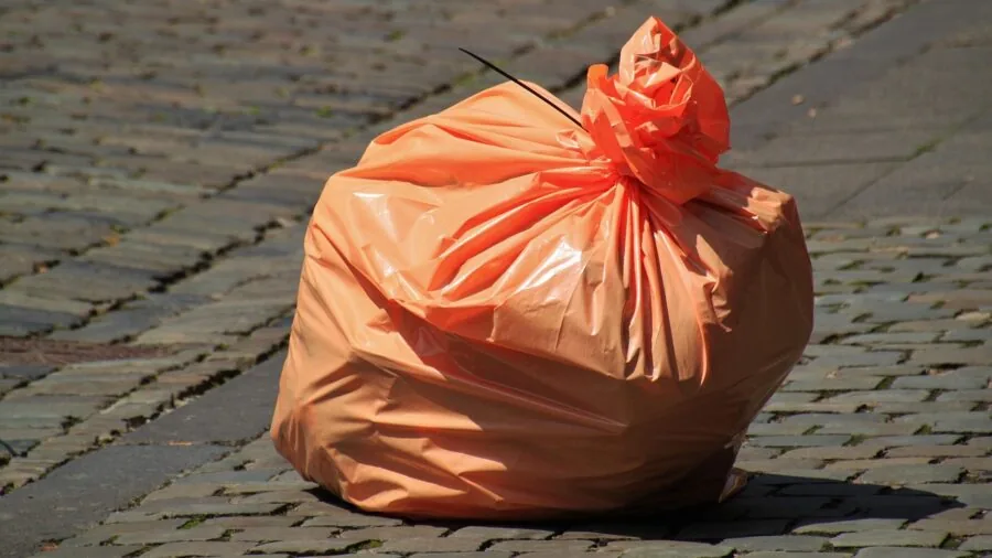 Dog owner on walk carrying waste bag dispenser while walking pet on leash