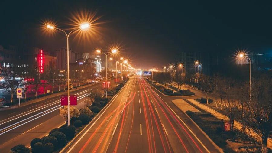 Driver backing up car at night with bright reverse lights illuminating the road behind the vehicle