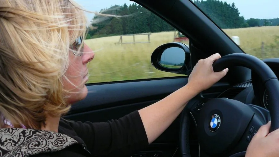 Driver glancing at phone mounted on car windshield during daytime drive