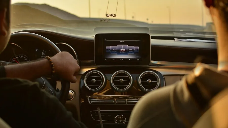 Driver glancing at smartphone mounted on car dashboard while driving on road