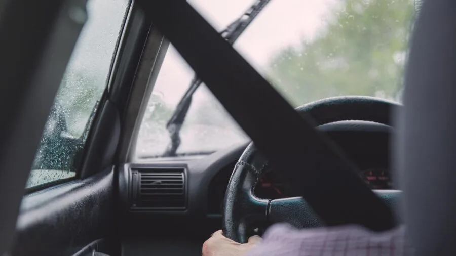 Driver's hands on steering wheel during temperature changes, showing seasonal driving conditions