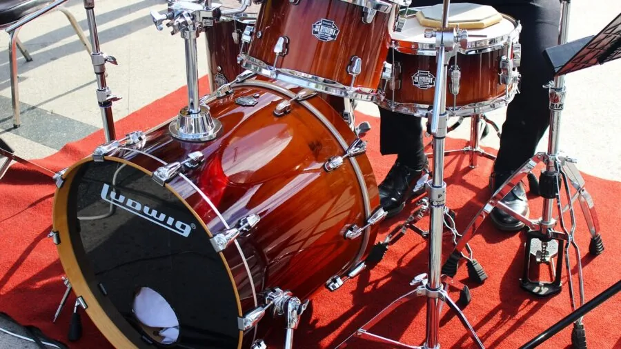 Drummer performing on acoustic drum kit in studio setting with natural lighting