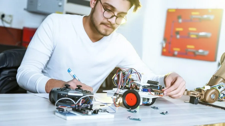 Engineer adjusting oscilloscope settings while testing electronic circuit in laboratory workspace