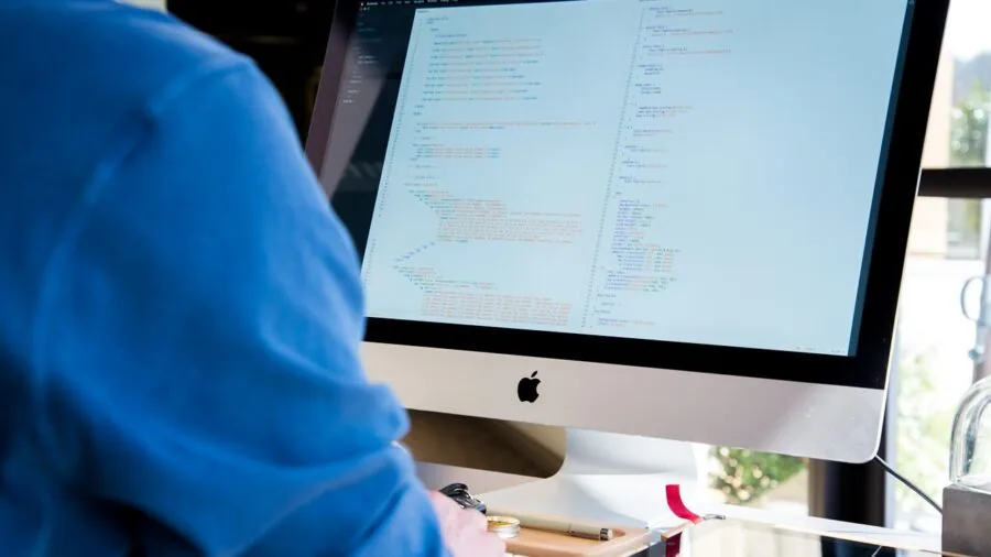Engineer at workstation with multiple monitors and electronic equipment in modern laboratory environment