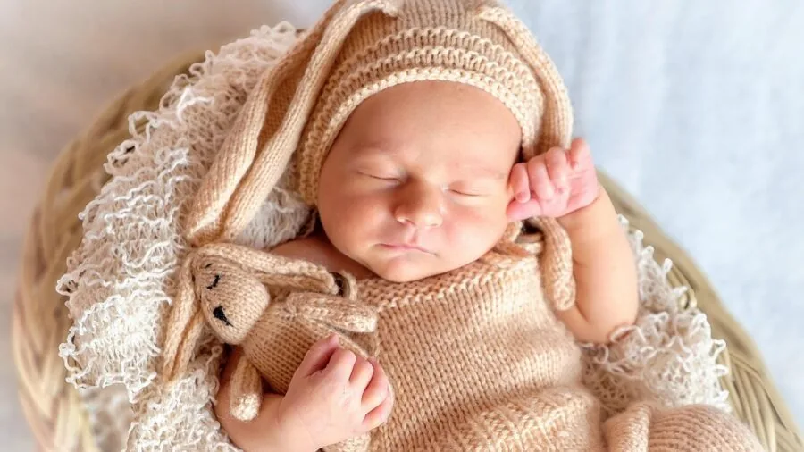 Exhausted parent holding baby during nighttime feeding in dimly lit bedroom
