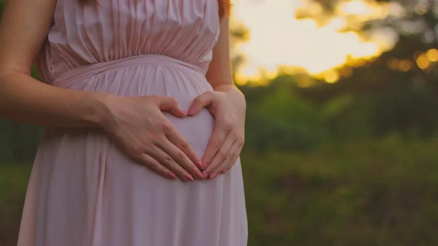 Expectant mother carefully examining vitamin bottle label in natural home lighting