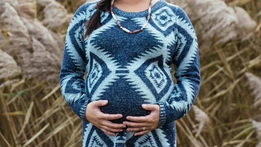 Expectant mother in comfortable maternity dress standing outdoors in natural daylight