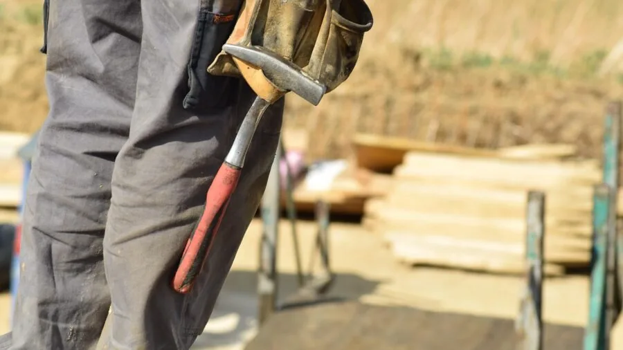Experienced tradesperson gripping and swinging a steel hammer during construction work on a wooden project
