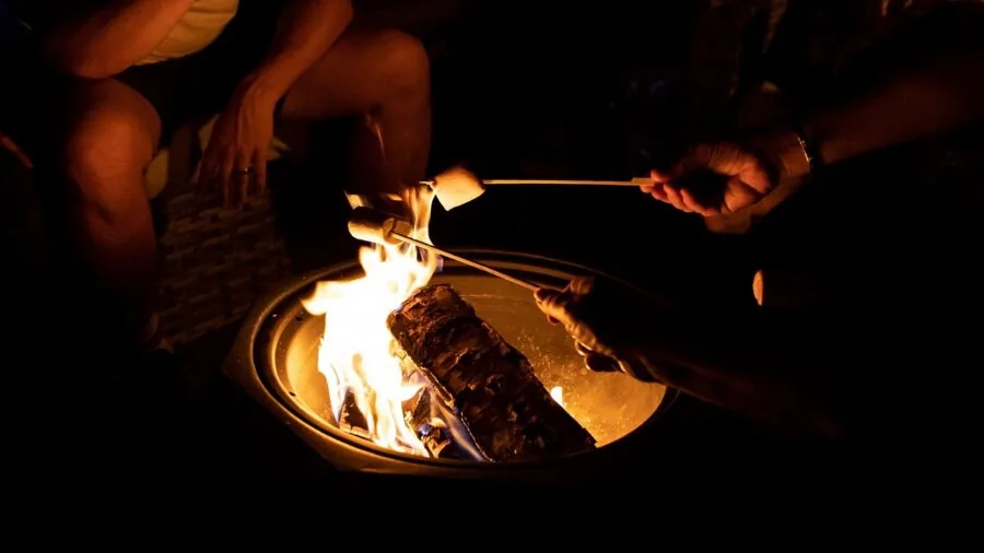 Family enjoying time safely around a backyard fire pit with protective screening in evening setting