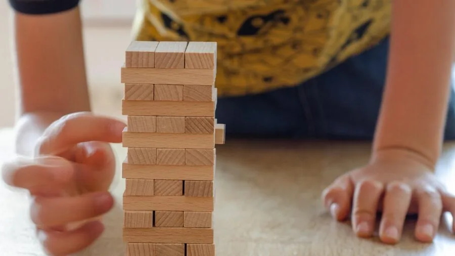 Family gathered around table playing board game, focusing on hands and game components during gameplay