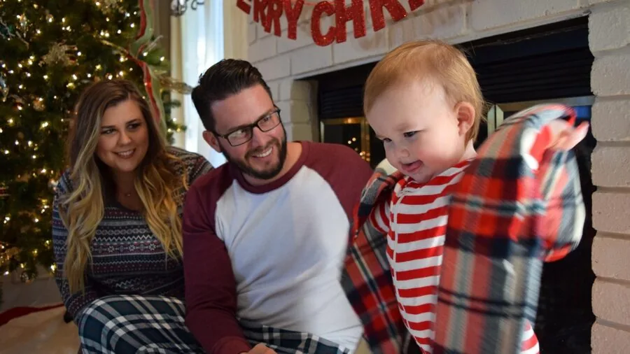 Family in coordinating holiday pajamas relaxing together during Christmas morning celebration