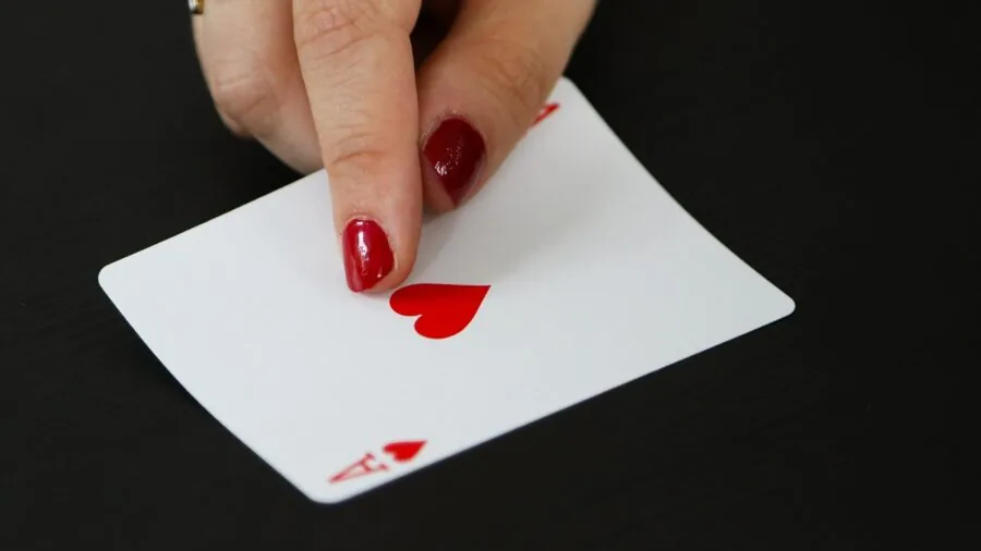 Family members gathered around table playing card game with expressions of excitement and engagement