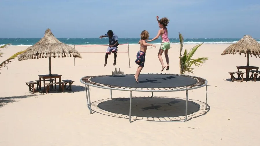 Family members jumping together on a round trampoline in a sunny backyard during daytime