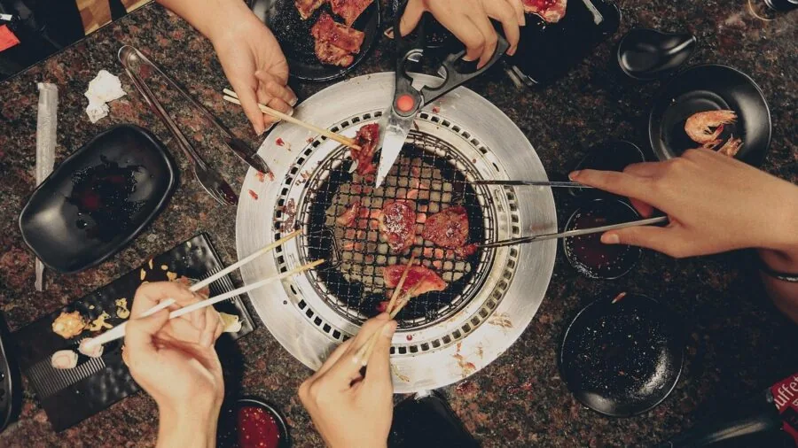 Family preparing food together on an outdoor grill during a casual backyard meal