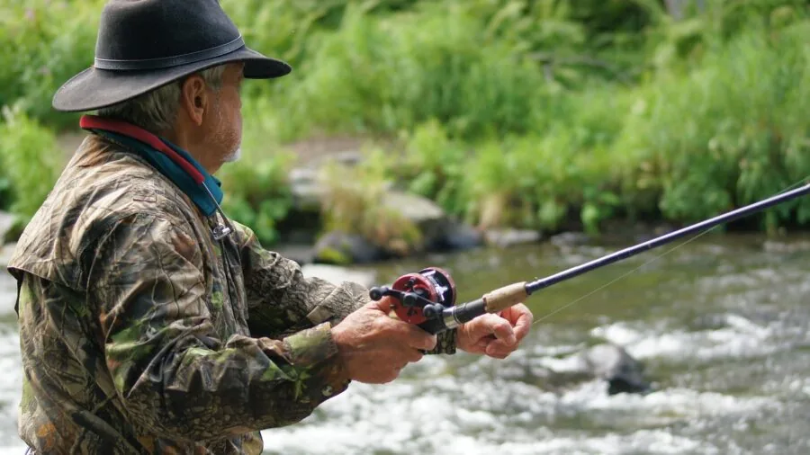 Fisherman casting rod from boat on open water during daytime fishing