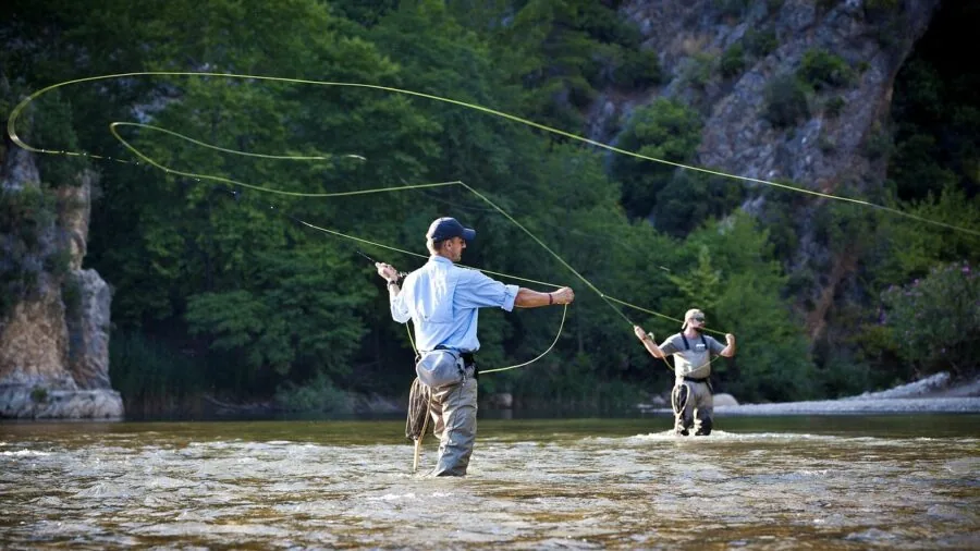 Fisherman casting rod into calm water during outdoor fishing adventure