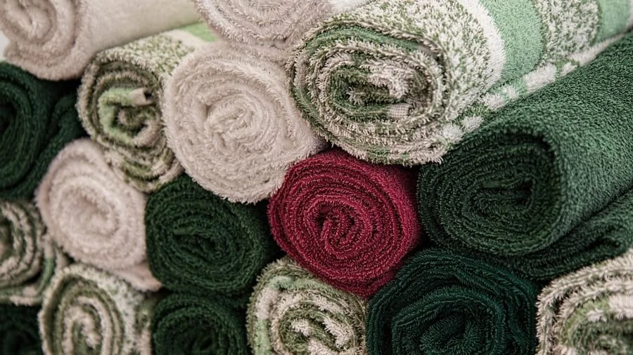 Fluffy white cotton towels folded neatly in a bright, modern bathroom setting with natural light