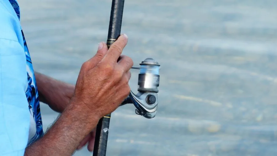 Fly fisherman's hands adjusting reel mechanism during river fishing preparation