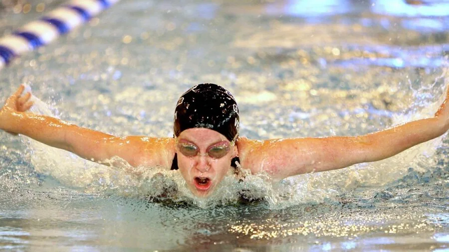 Focused swimmer doing lap strokes in indoor pool during training session