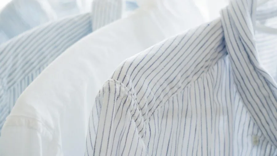 Fresh white linen sheets being folded after washing, showing natural texture and softness