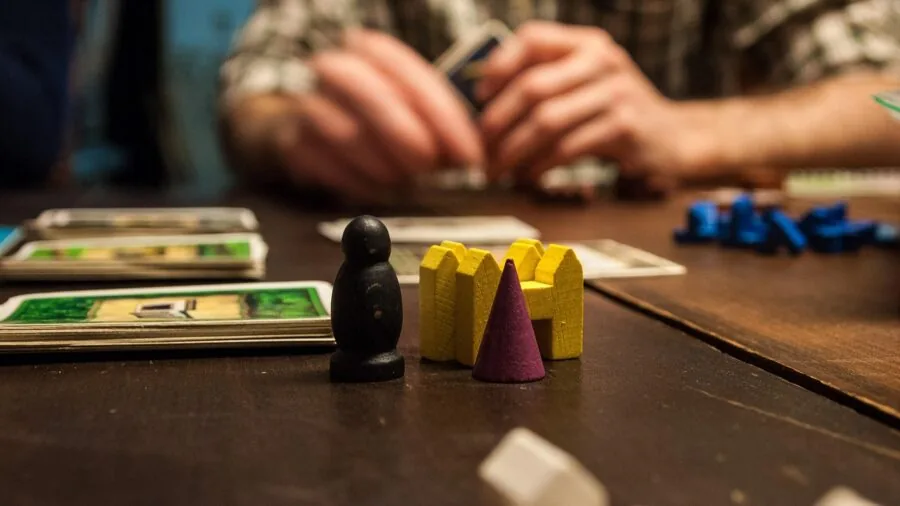 Friends gathered around table learning new board game rules with instruction manual