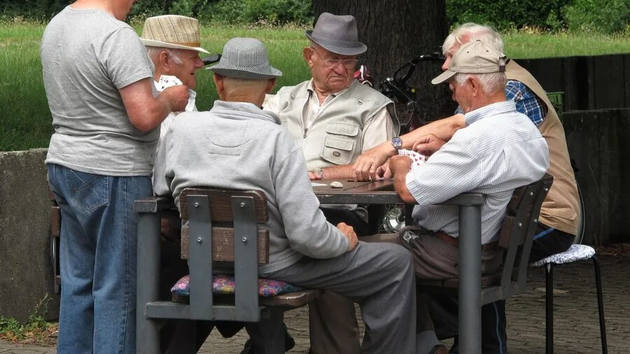Friends gathered around table playing card game with focused expressions and tension