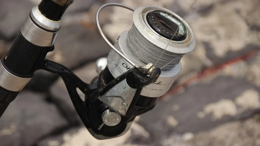 Frustrated fisherman working to untangle knotted fishing line during outdoor fishing trip