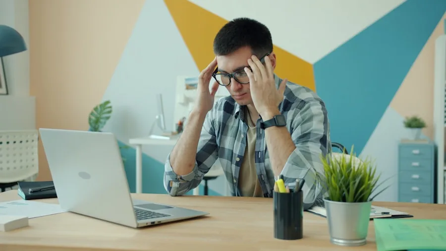 Frustrated person dealing with tangled wired earbuds at a desk workspace