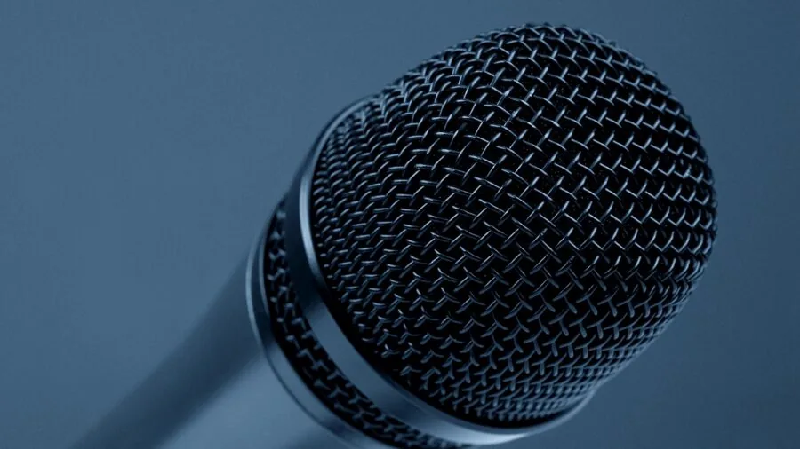 Frustrated person holding microphone experiencing audio feedback issues during public speaking or presentation
