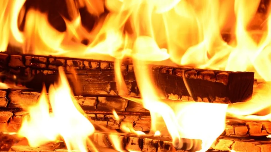 Glowing campfire with steady flames consuming wooden logs in outdoor setting