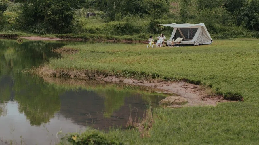 Glowing lantern illuminating a rustic campsite at dusk with tent and natural surroundings