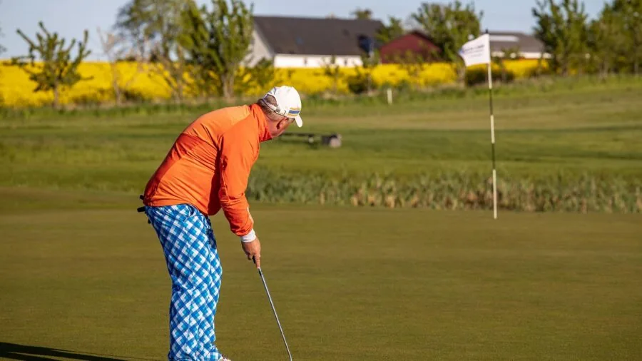 Golfer adjusting putter length and stance position during practice on golf course