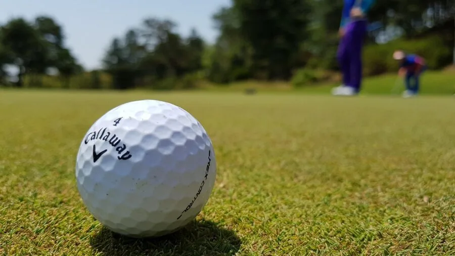 Golfer checking distance and ball trajectory on golf course fairway during game