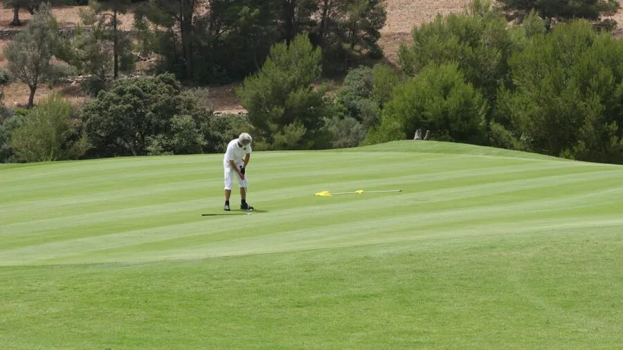 Golfer demonstrating putting technique on green during round of golf