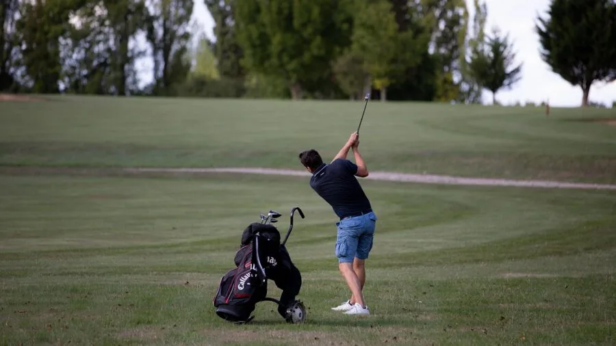Golfer examining and choosing golf clubs while standing on the fairway during a round
