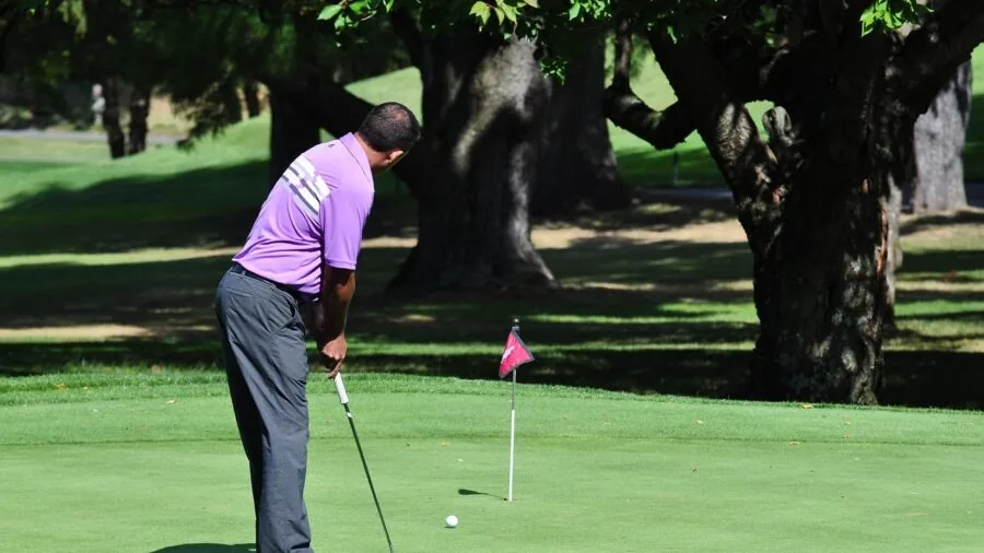 Golfer focusing on putter alignment before putting on golf course green